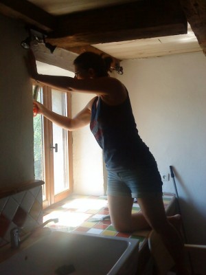Marie gratte le plâtre de la fenêtre de la cuisine avant de pouvoir mettre les "petits bois