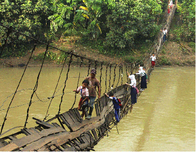 Des écolières traversent un pont suspendu et délabré à Lebrak en Indonésie